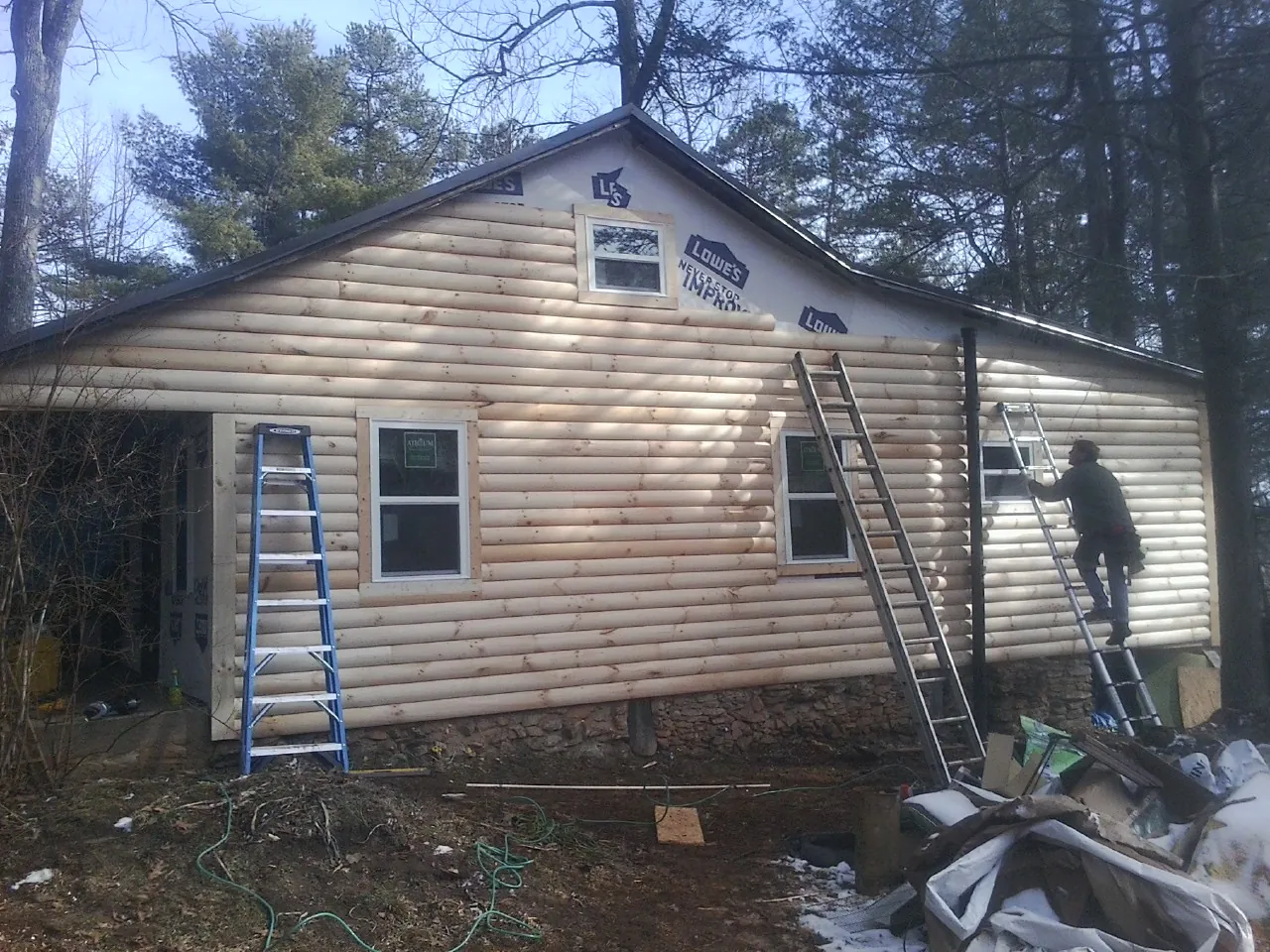 Ladders set against fresh log siding during an exterior remodel in Gilby