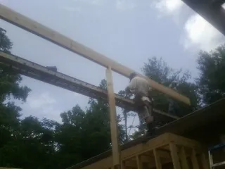 Carpenter setting a ridge beam over a new addition frame — Ice Dam Removal by Roofing Brothers in Gilby