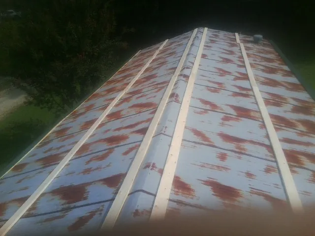 Rusted metal roof panels with new wood purlins before replacement — Storm Damage Roof Repair in Gilby by Roofing Brothers