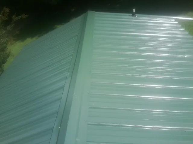 New green metal panels meeting at the ridge of a roof — Flat Roof Repair work by our crew in Gilby