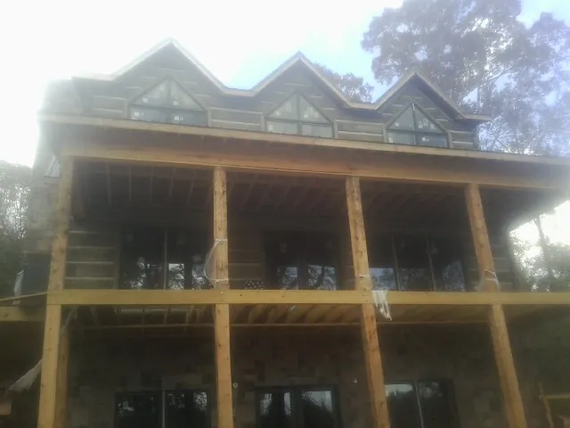 Dormers and porch framing on a large log home under construction — Roof Coating work by our crew in Gilby