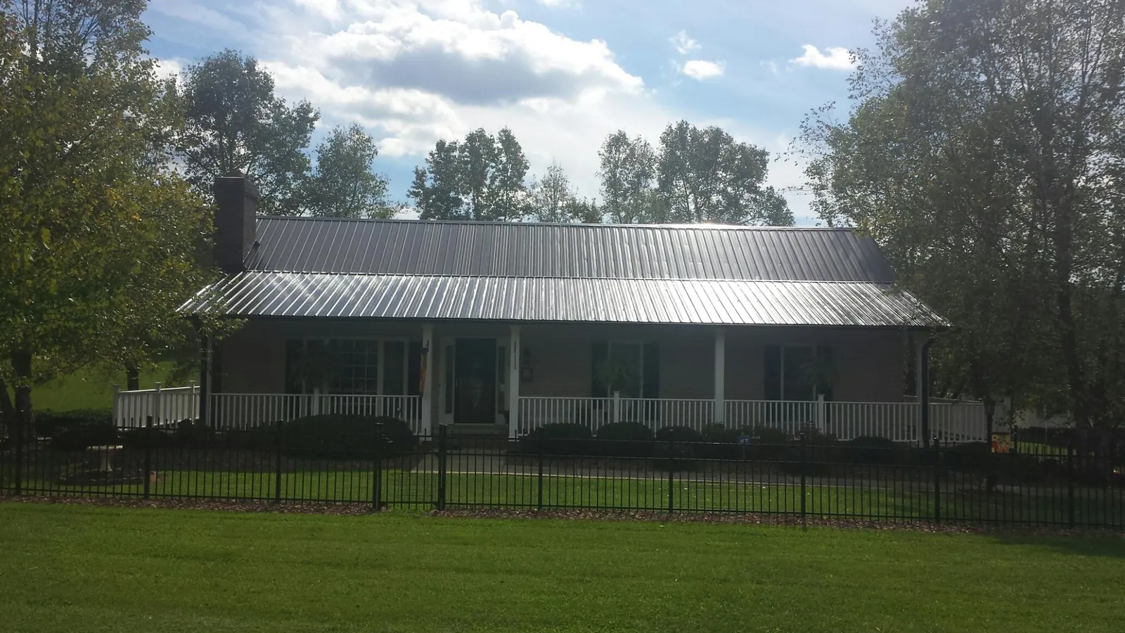 Gray metal roof on a brick ranch with a full width front porch — Gutter Guard Installation work by our crew in Gilby